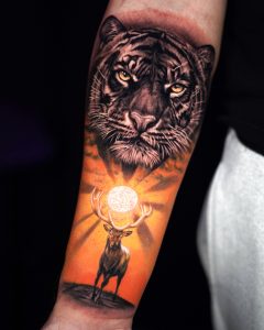 Tätowierung, die einen Tiger mit einer Sonne und einem Hirsch darunter darstellt.