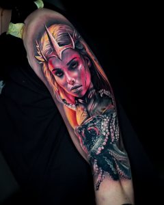 Tätowierung, die eine Fantasiefigur in Gestalt einer Frau darstellt, mit einer dreizackigen Krone auf dem Kopf und einem Oktopus unter ihr.