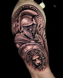 Tätowierung, die einen Krieger darstellt, der einen Helm auf dem Kopf trägt und einen Helm in der Hand hält, auf dem das Gesicht eines Löwen eingraviert ist.