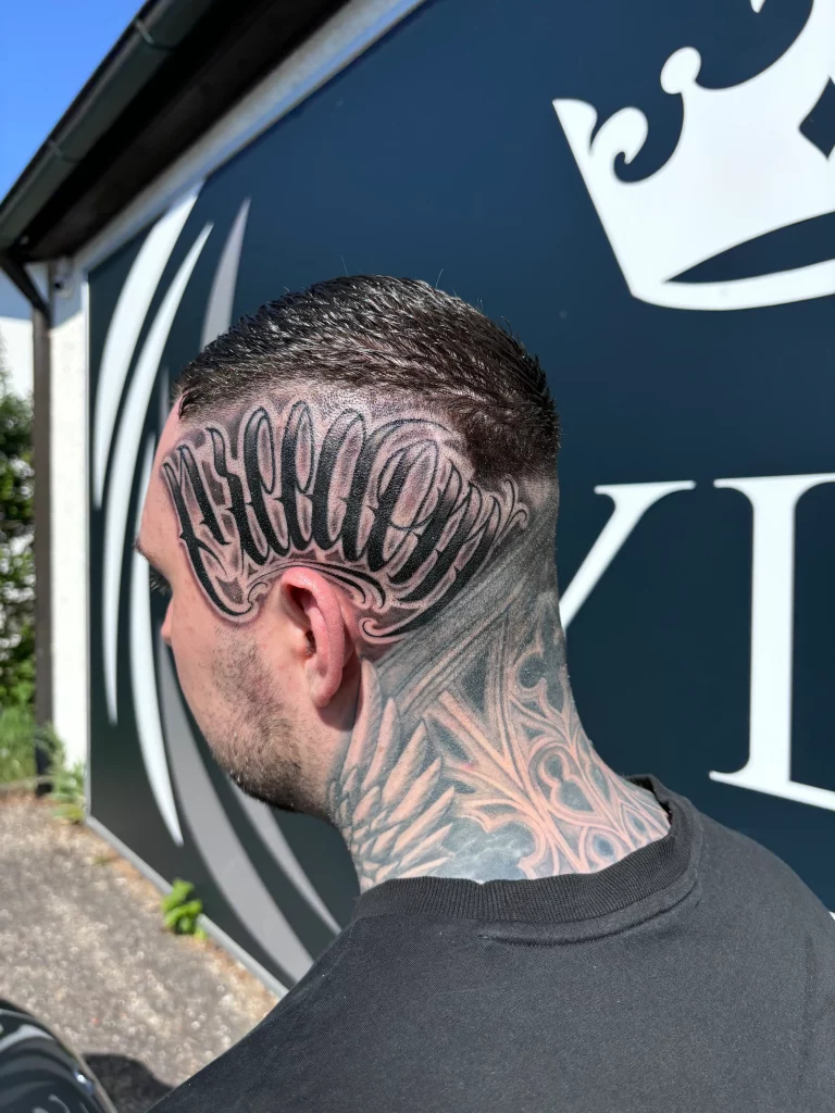 Großflächiges Kopf Tattoo im Lettering und Blackwork Stil mit auffälliger Schrift und nahtlosem Übergang zum Nacken Tattoo - detailreiches Tattoo für maximale Ausdrucksstärke, Individualität und kompromisslose Ästhetik - präzise gestochen bei Skyline Tattoo® in Rohrbach Bayern nahe München und Ingolstadt, spezialisiert auf anspruchsvolle Kopf Tattoos, Lettering und großflächige Blackwork Projekte