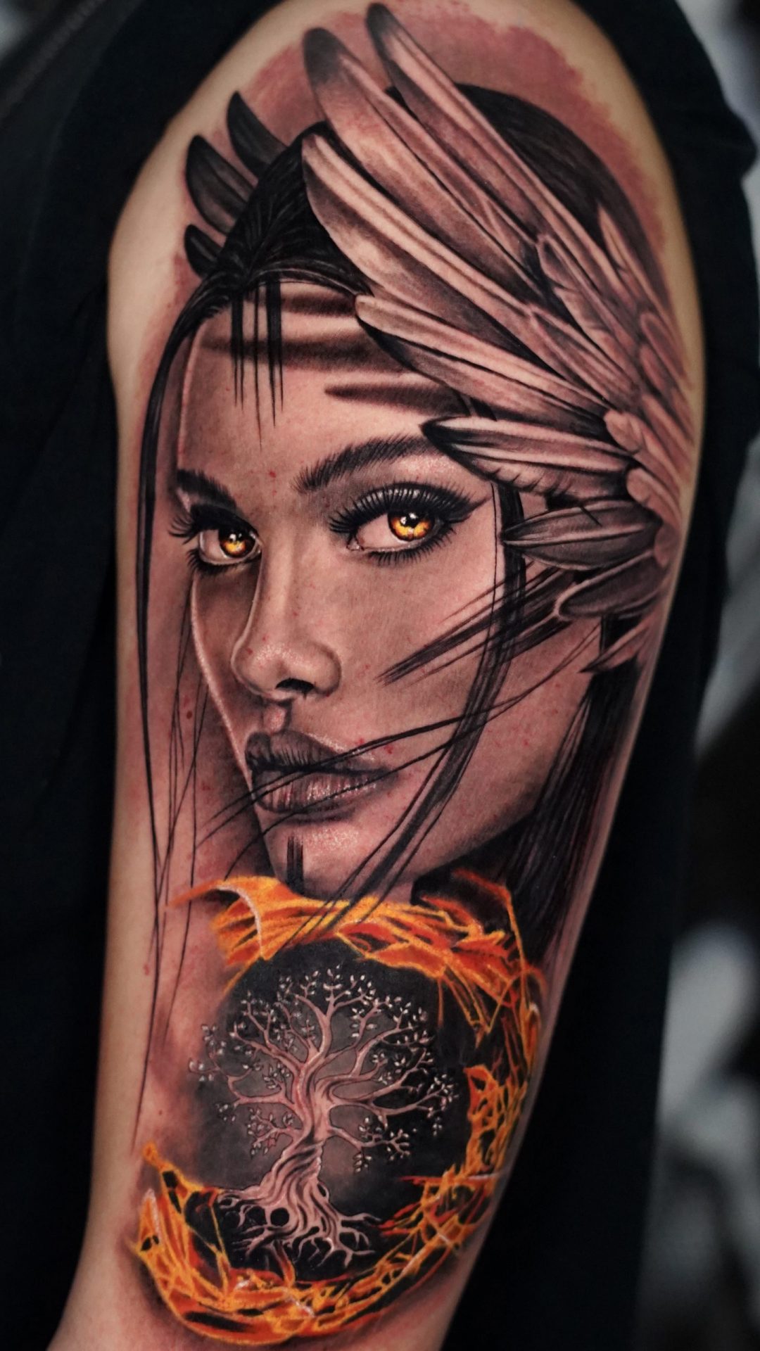 Realistisches Oberarm Tattoo eines Frauenportraits mit Federn und Feuer-Element in Farbe - gestochen bei Skyline Tattoo