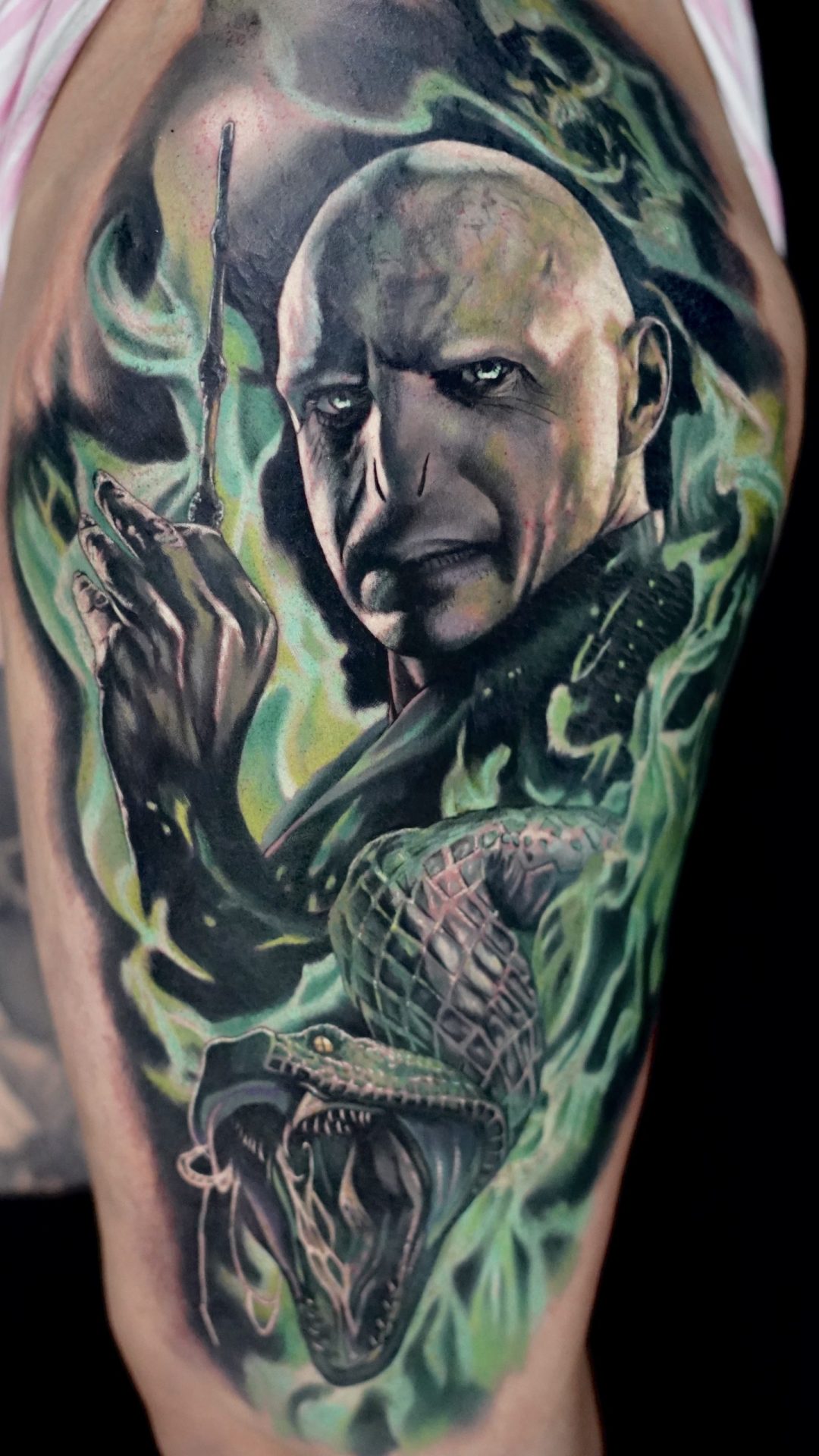 Tätowierung, die Lord Voldemort umgeben von grünem Rauch darstellt, unter ihm seine Schlange Nagini