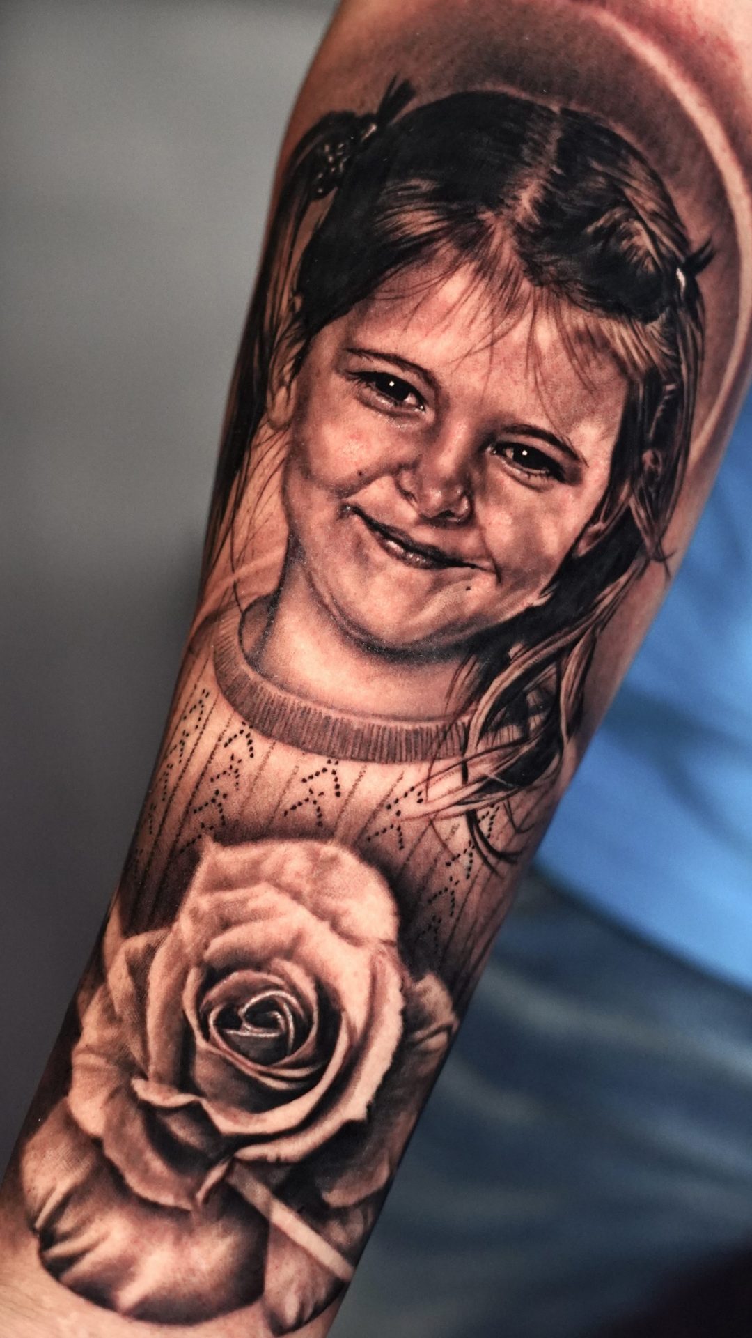 Porträt-Tätowierung, die ein kleines Mädchen mit einer Rose darunter darstellt